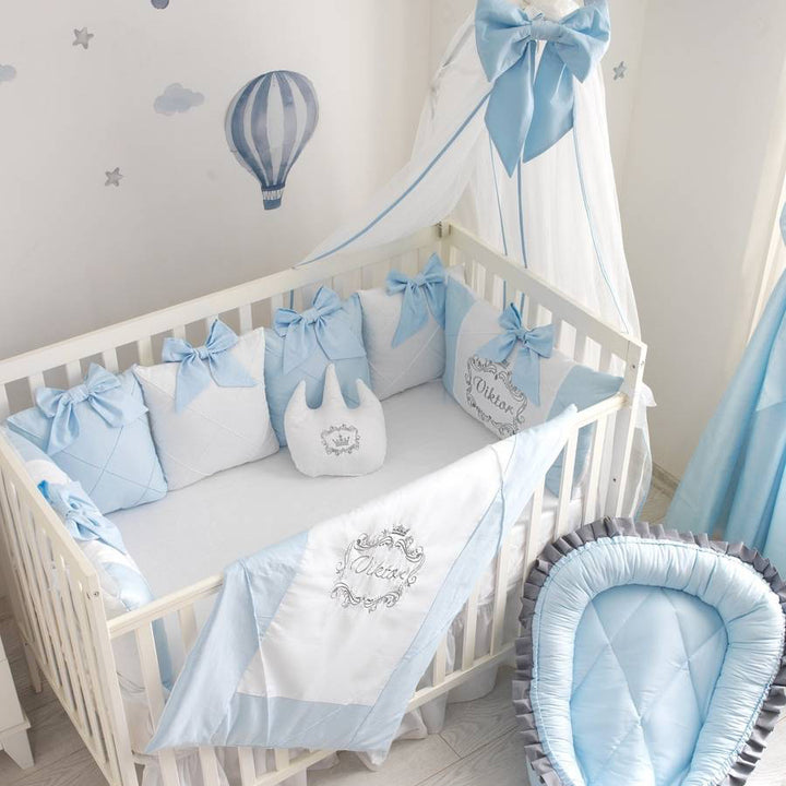 Baby crib with blue and white bedding and canopy in a nursery.