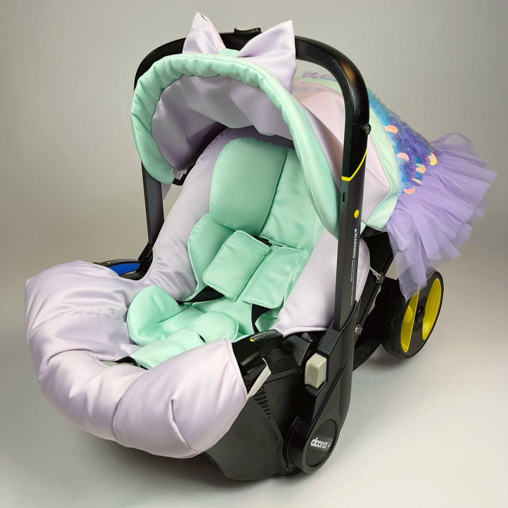 Baby car seat with a green cushion and purple cover on a gray background
