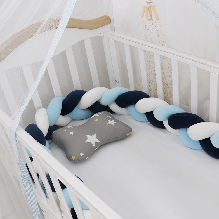 A braided crib bumper set in a crib, featuring a mix of light and dark blue braids with a gray end pillow decorated with a star.