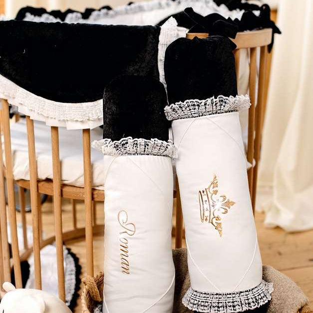 Decorative black and white stockings with lace trim and embroidered text on a wooden chair.