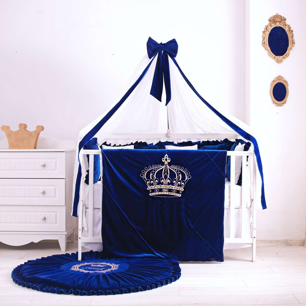 A luxury blue and white velvet baby bedding set displayed on a crib, with a personalized blanket and matching rug, in a nursery room.