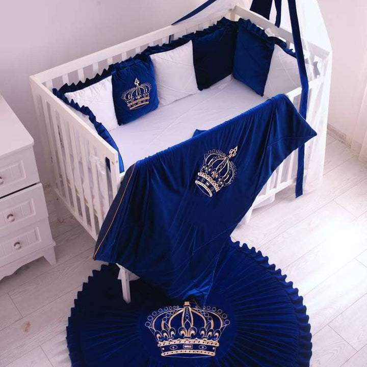 Navy blue crib set with crowns and white crib in a room.