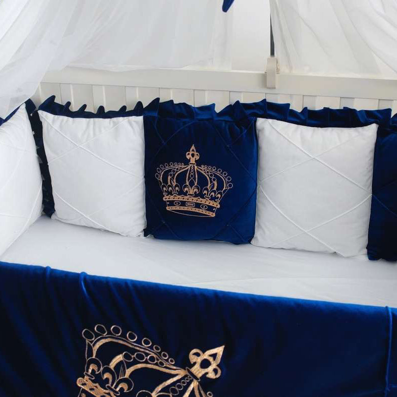 blue and white crib set with embroidered crowns on a white crib.