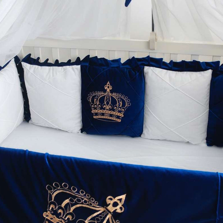 blue and white crib set with embroidered crowns on a white crib.